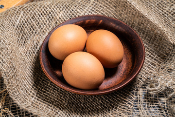 Eggs in a clay bowl on a background of natural fabric. The concept of making bread, home baking