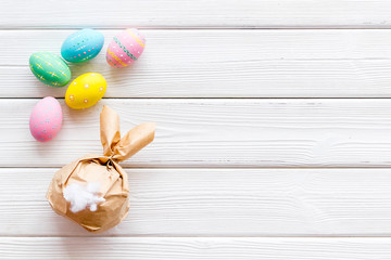 Easter symbols. Bunny and painted eggs on white wooden background top-down frame copy space