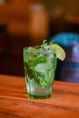 Classic fresh mojito on the table in a bar. Alcohol cocktail with ice, mint and lime on table with...