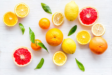 Fresh citrus background. Oranges, grapefruits, leaves - whole fruits and halfs - on white background top-down