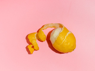 Lemon with spiral peeled zest over pink minimalistic background. Lemon and peel in hard light. Top...