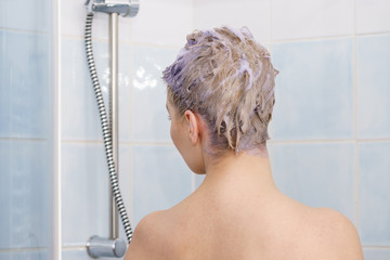 Woman under the shower with colored foam on hair