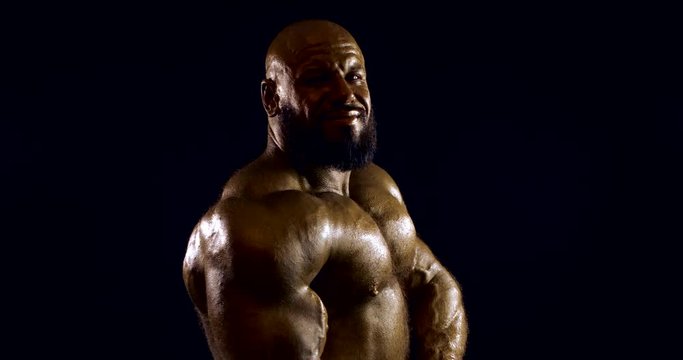 strong body-builder poses for camera showing muscles
