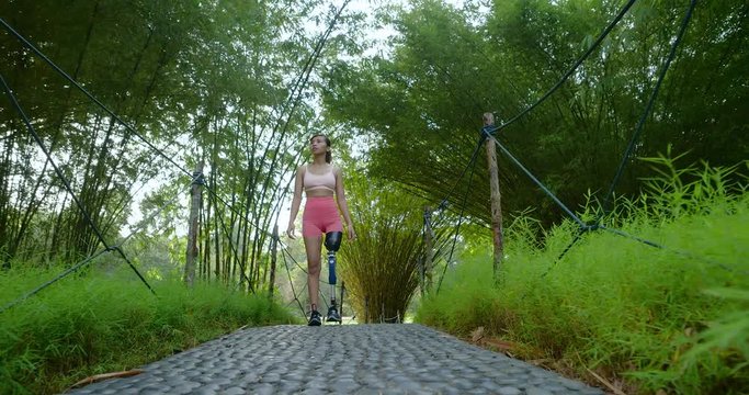 Leg Amputated Asian girl walking inside bamboo garden after finishing her morning workout session
