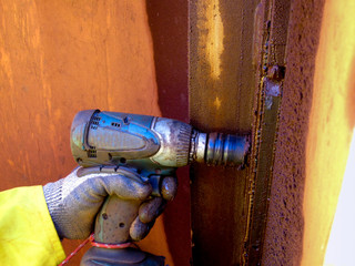 Worker wearing a industrial heavy duty glove protection while using rattle gun to removing...