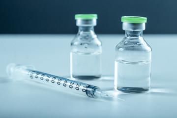 Vaccine in vial and syringe close-up on a white table gray background, medical concept, laboratory,...