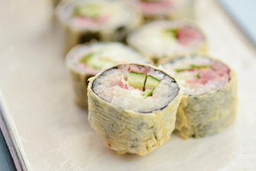 Maki Sushi California fried hot rolls with fresh salmon, cucumber and cream cheese philadelphia inside on white plate