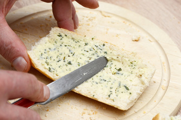 spread rustic crusty white bread with Herb butter in the kitchen
