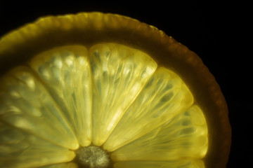 Juicy slice of lemon on a dark background. In the frame, only part of the citrus. Detailed macro...