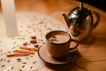 Brown cup of coffee latte or americano with milk on rustic wooden table with sugar and cinnamon and anise.