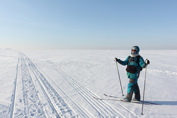 Happy woman with a photo bag, backpack and video camera, skiing on the snow surface on a frozen...