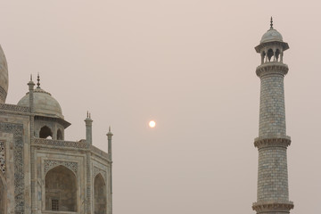Looking up at the Taj Mahal in Agra, India, on overcast morning with small red sun