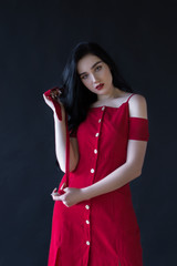 beautiful girl with black hair and a red dress holding a belt from a dress in her hands