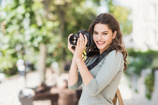 Woman professional photographer with dslr camera outdoors portrait.  Pretty young girl in the city taking images with photo camera