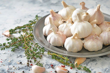 Plate with fresh garlic and herbs on white background