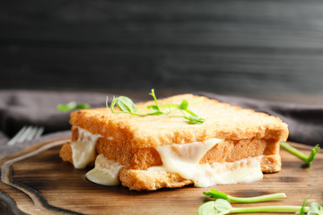 Tasty sandwich with cheese on wooden board
