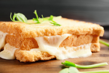 Tasty sandwiches with cheese on wooden board, closeup