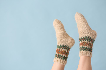 Legs of young woman in warm knitted socks on color background
