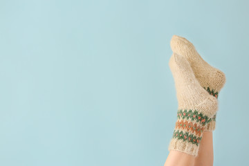 Legs of young woman in warm knitted socks on color background