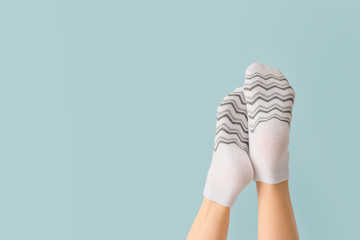 Legs of young woman in socks on color background