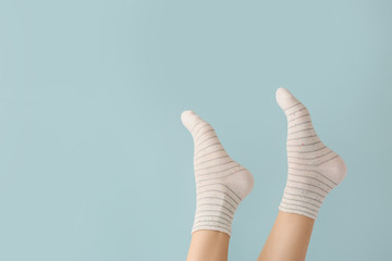 Legs of young woman in socks on color background