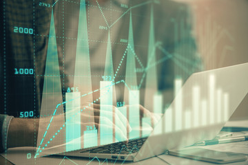Double exposure of market chart with man working on computer on background. Concept of financial...