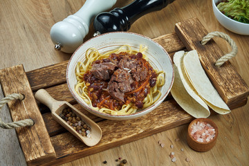 Mexican style noodles - corn paste with chili con carne, stewed beef and tacos in a ceramic plate....