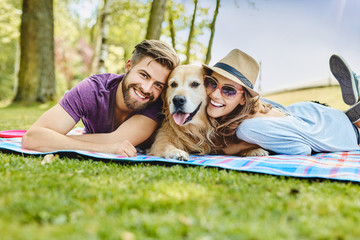 Young couple with dog, having fun during summer picnic in the park