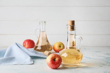 Bottles of apple cider vinegar on white table