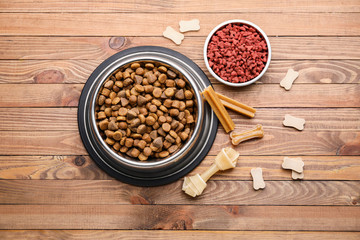 Bowls with dry pet food on wooden background