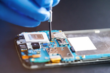 Asian Technician repairing micro circuit main board of smartphone electronic technology : computer,...
