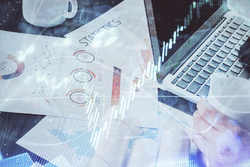 Obraz premium Double exposure of stock graph with businessman typing on computer in office on background. Concept of hard work.