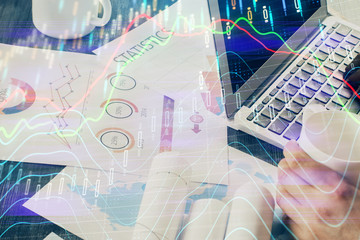 Double exposure of stock graph with businessman typing on computer in office on background. Concept...