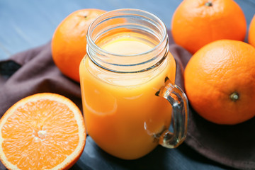 Mason jar of fresh orange juice and fruit on table