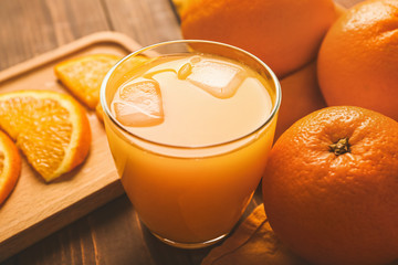 Glass of fresh orange juice and fruit on table