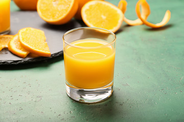 Glass of fresh orange juice on color background