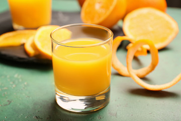 Glass of fresh orange juice on color background