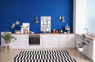 Interior of modern kitchen with blue wall