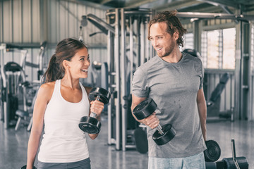 Fitness gym personal trainer coach training Asian woman with free weights dumbbell bicep curls...