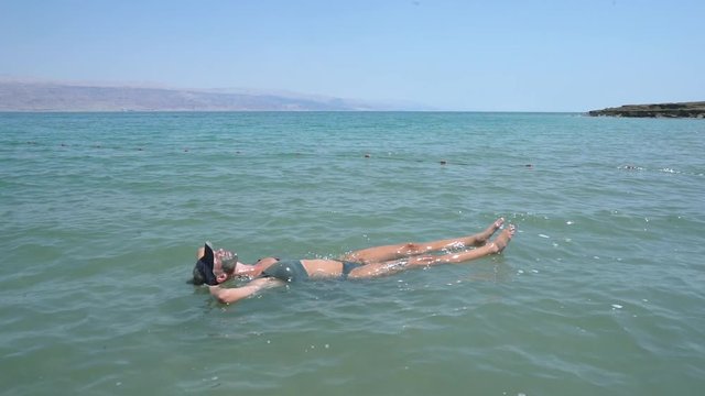 Slow motion fit tourist in bikini floating in the dead sea israel
