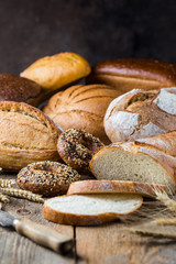 Assortment of fresh baked bread and buns on wooden table background