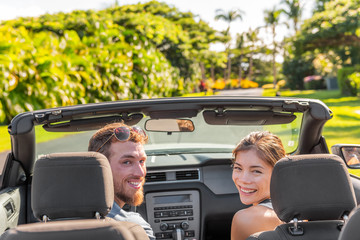 Happy road trip couple having fun driving luxury sports convertible car rental on travel vacation...