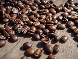 Black coffee in grains on the surface of a wooden table.
