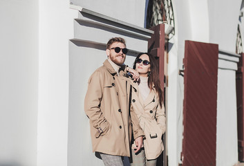 trendy young couple in coat posing in the city in springtime
