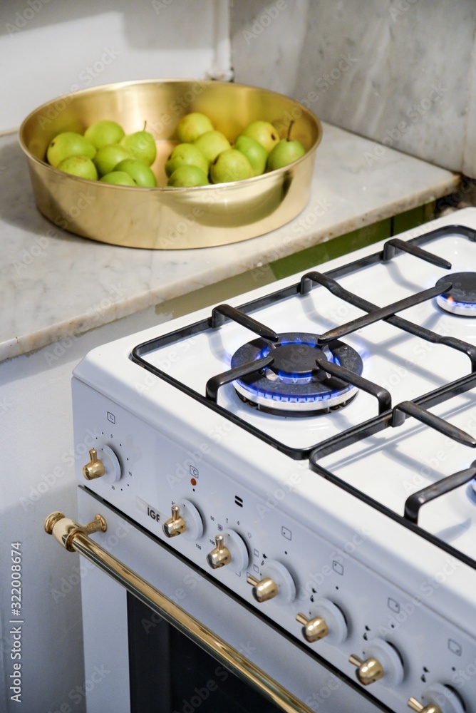 Poster vertical high angle shot of a burning stove and a bowl with pears in the kitchen