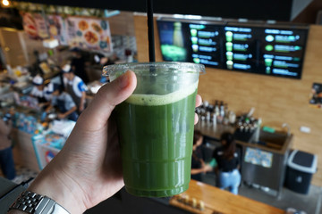 Close up Hand holding a plastic take away cup of Iced Matcha green tea