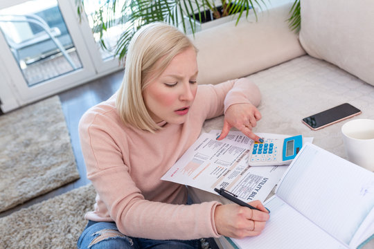 Candid Shot Of Beautiful Young Albino Woman Sitting With Calculator And Bills, Doing Paperwork. Hand Woman Doing Finances And Calculate On Desk About Cost At Home Office.Concept Finances And Economy