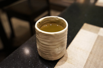 Close up ceramic cup of hot Matcha green tea on wooden table