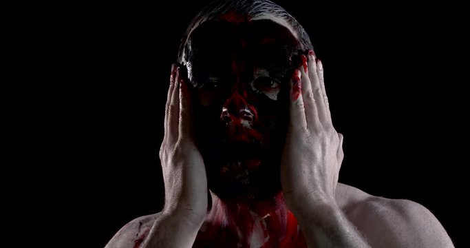 madman smears paint over face and laughs expressing emotions