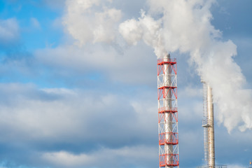 Air pollution from chimneys. Factory pipes with smoke on a background of gray-blue sky with clouds...